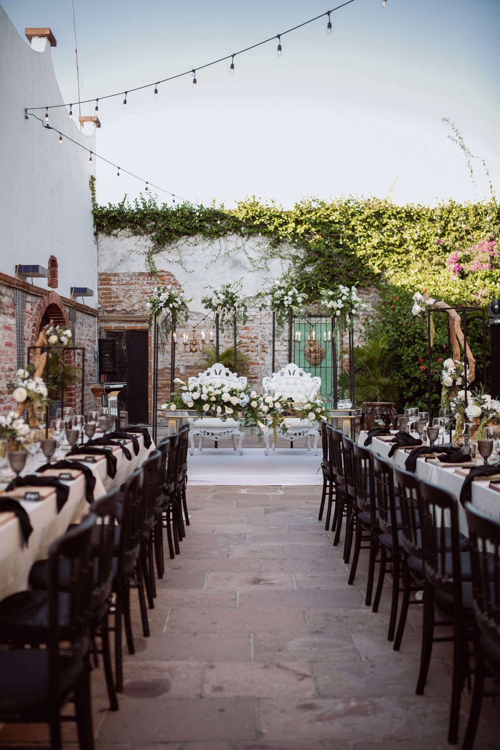 Mesa larga de boda al aire libre, con luces al anochecer